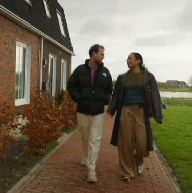 twee mensen lopen op de stoep voor een rij huizen