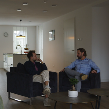 Gesprek tussen twee mannen in een woonkamer