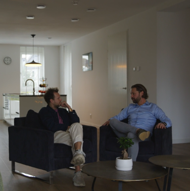 Gesprek tussen twee mannen in een woonkamer