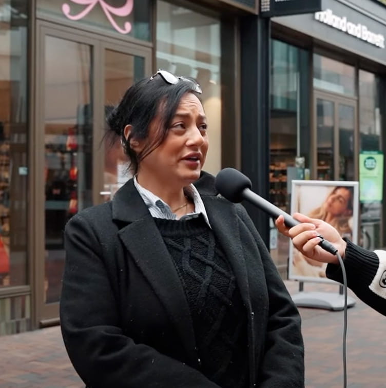 Vrouw geeft antwoord tijdens een straatinterview in een winkelstraat.