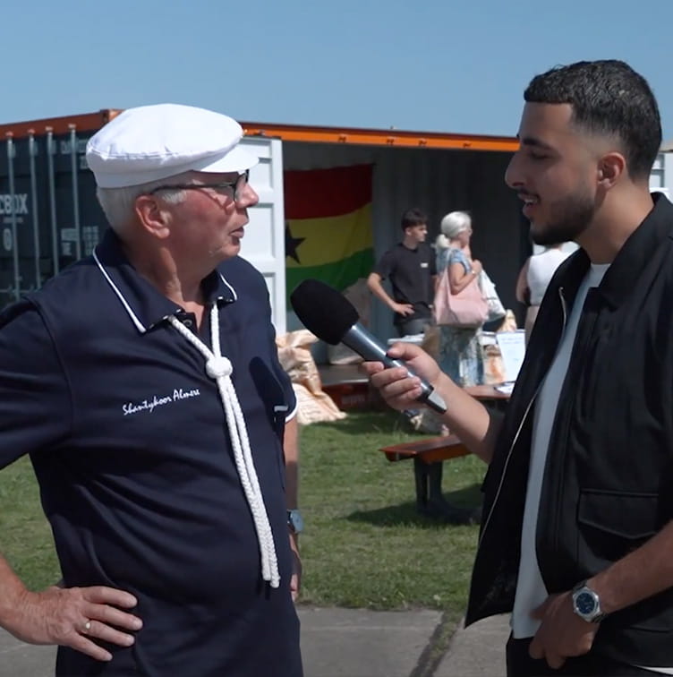Man interviewt oudere man met zeemanspet op de Zeehavendagen voor Straatvragen 