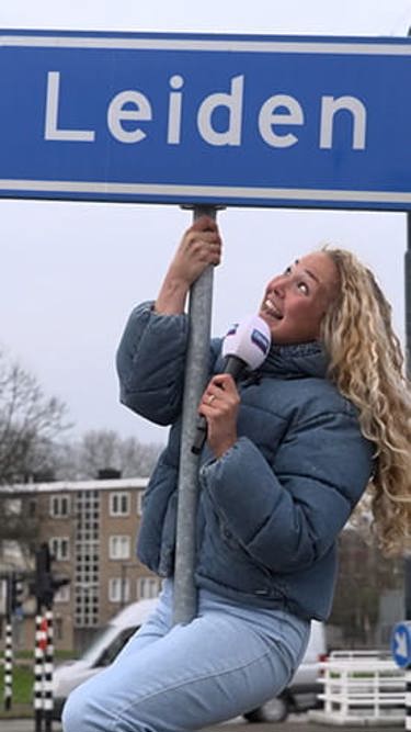 Romy klimt in een plaatsnaambord Leiden