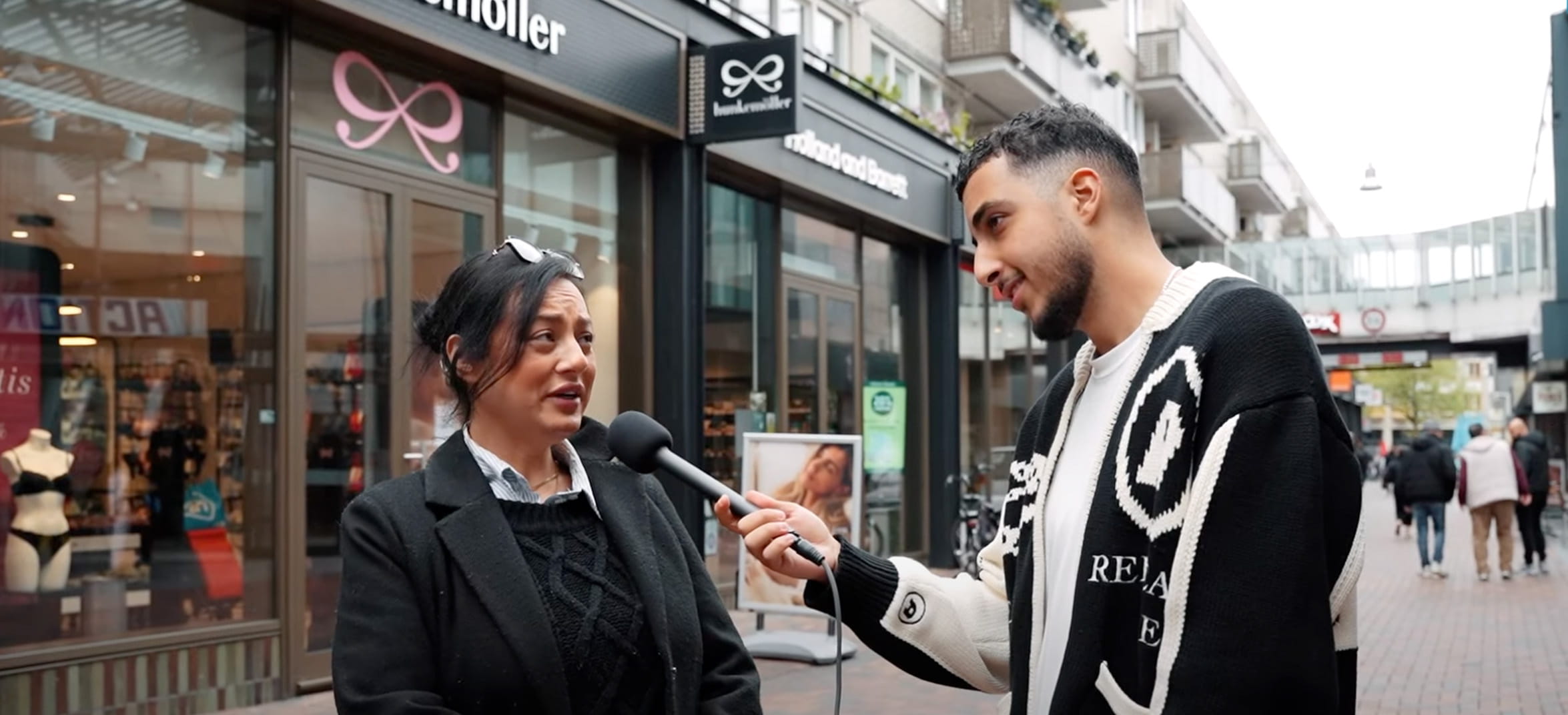 Vrouw geeft antwoord tijdens een straatinterview in een winkelstraat.