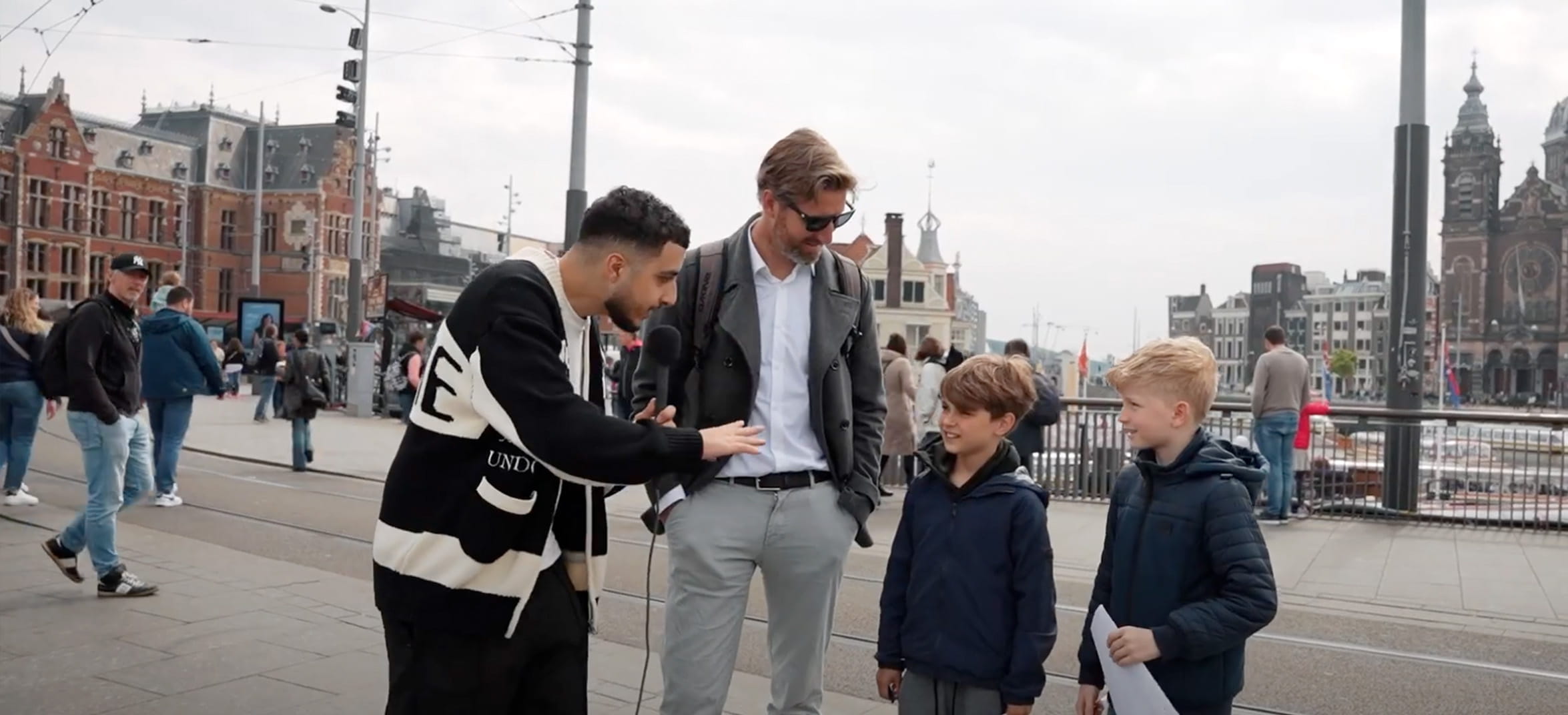 Rida van Liander interviewt vader en twee kinderen op straat bij Amsterdam Centraal Station