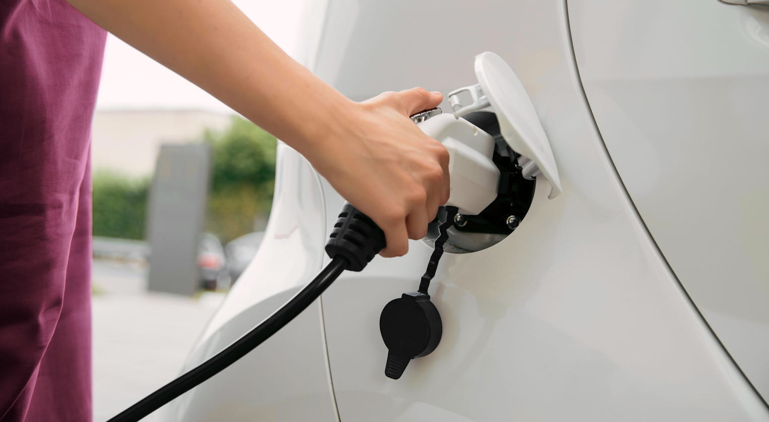Persoon laadt een elektrische auto op bij een laadpaal – duurzaam vervoer en elektrische mobiliteit