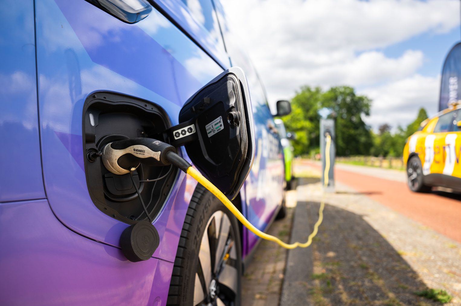 Elektrische bestelwagen laadt op bij een openbare laadpaal, met laadkabel aangesloten tijdens het opladen van emissievrije mobiliteit.