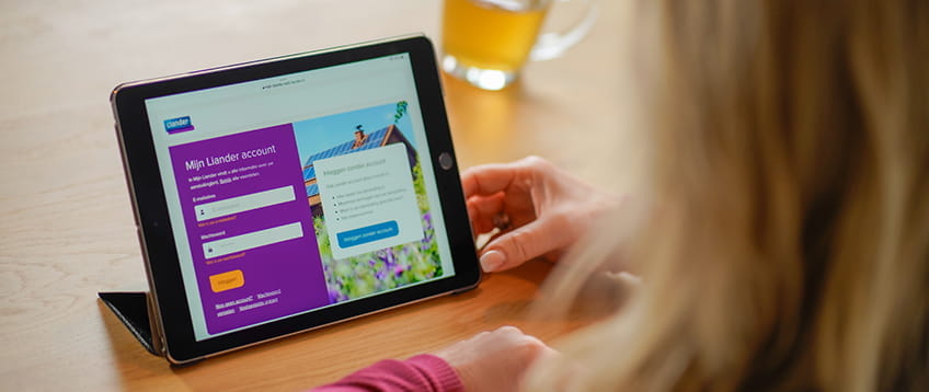 Je kijkt over de schouder van een blonde vrouw, die op haar Ipad op de website mijnliander.nl kijkt