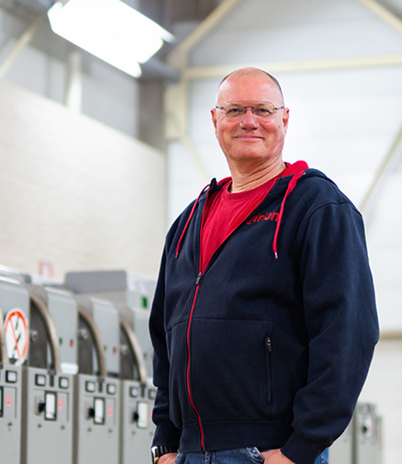 Persoon in een industriële hal met machines op de achtergrond.