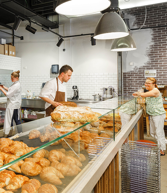 Je ziet drie mensen in een bakkerij.