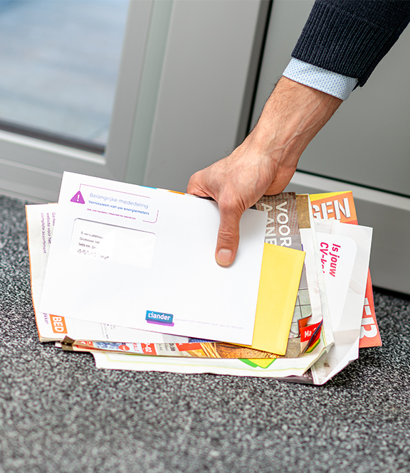 Een stapeltje enveloppen worden door een man van de deurmat gepakt