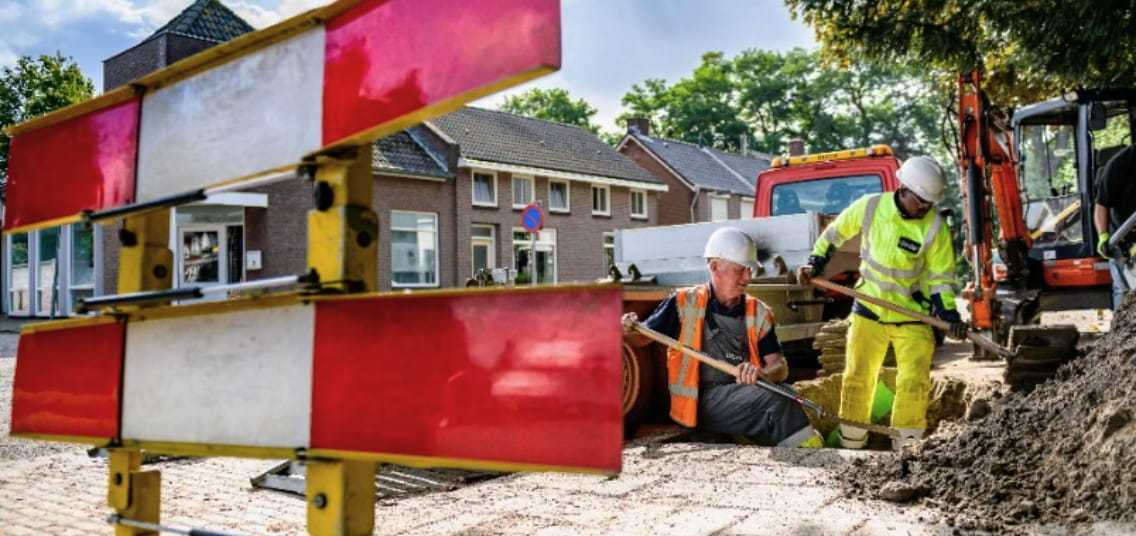 monteurs van Liander graven naar kabels in de straat. op de voorgrond staat een rood wit hek.