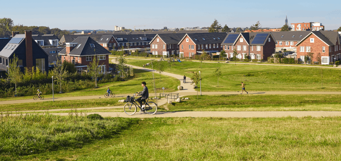 woonwijk met woningen met zonnepanelen. Op de voorgrond een park, met wandelende en fietsende mensen.